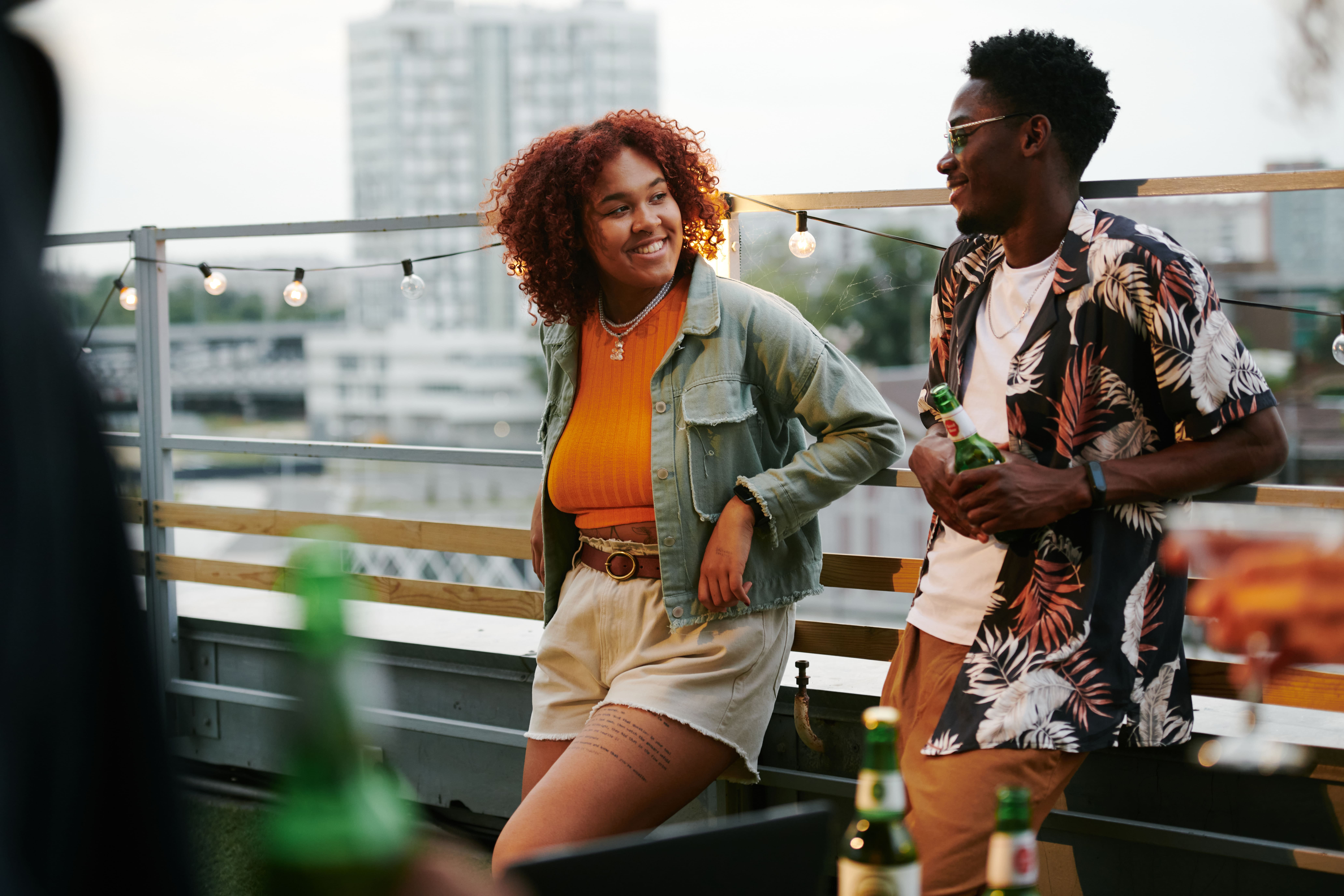 Homem e mulher negros conversam em um rooftop