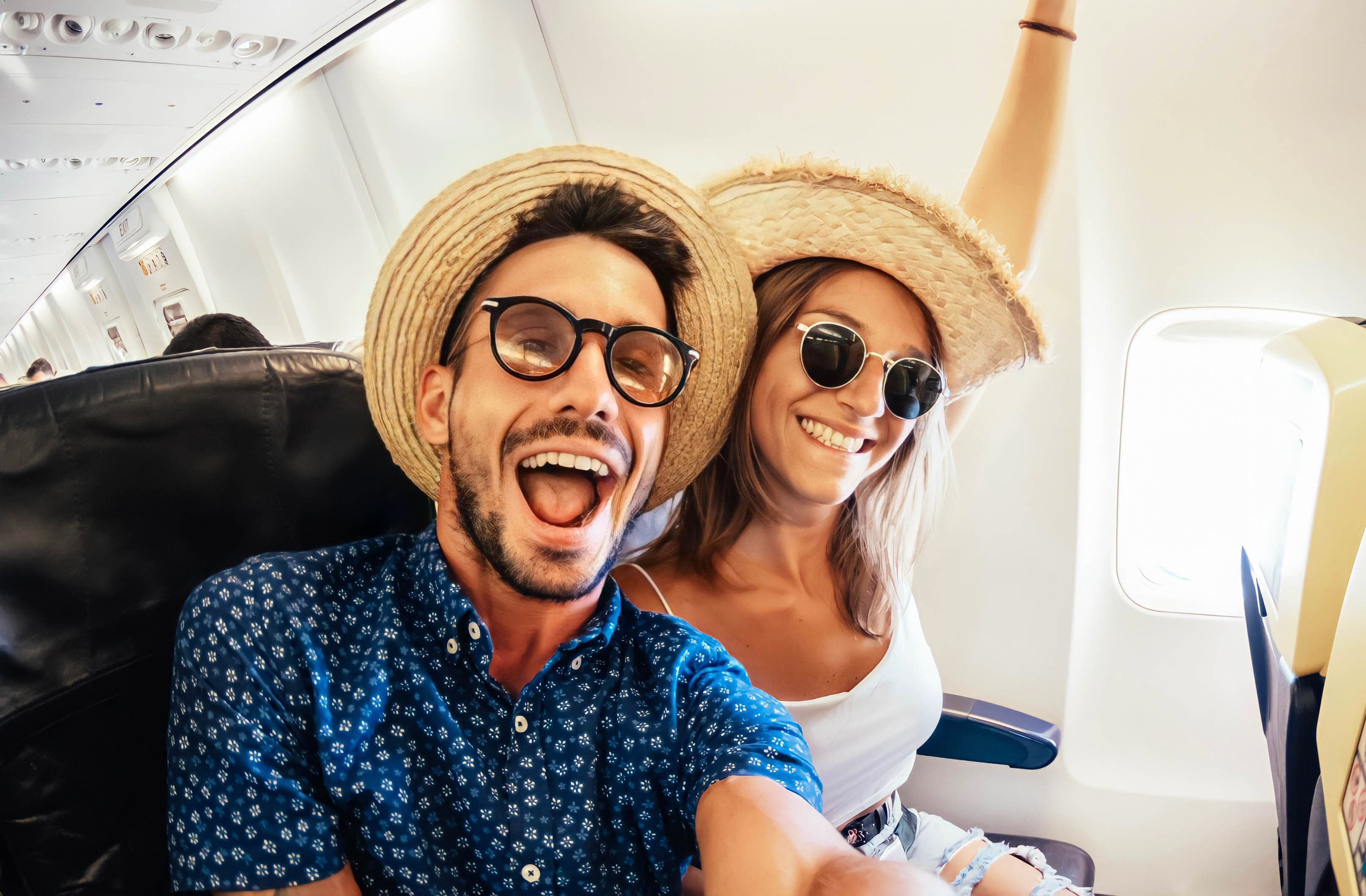 Casal de turistas felizes tiram selfie dentro do avião.