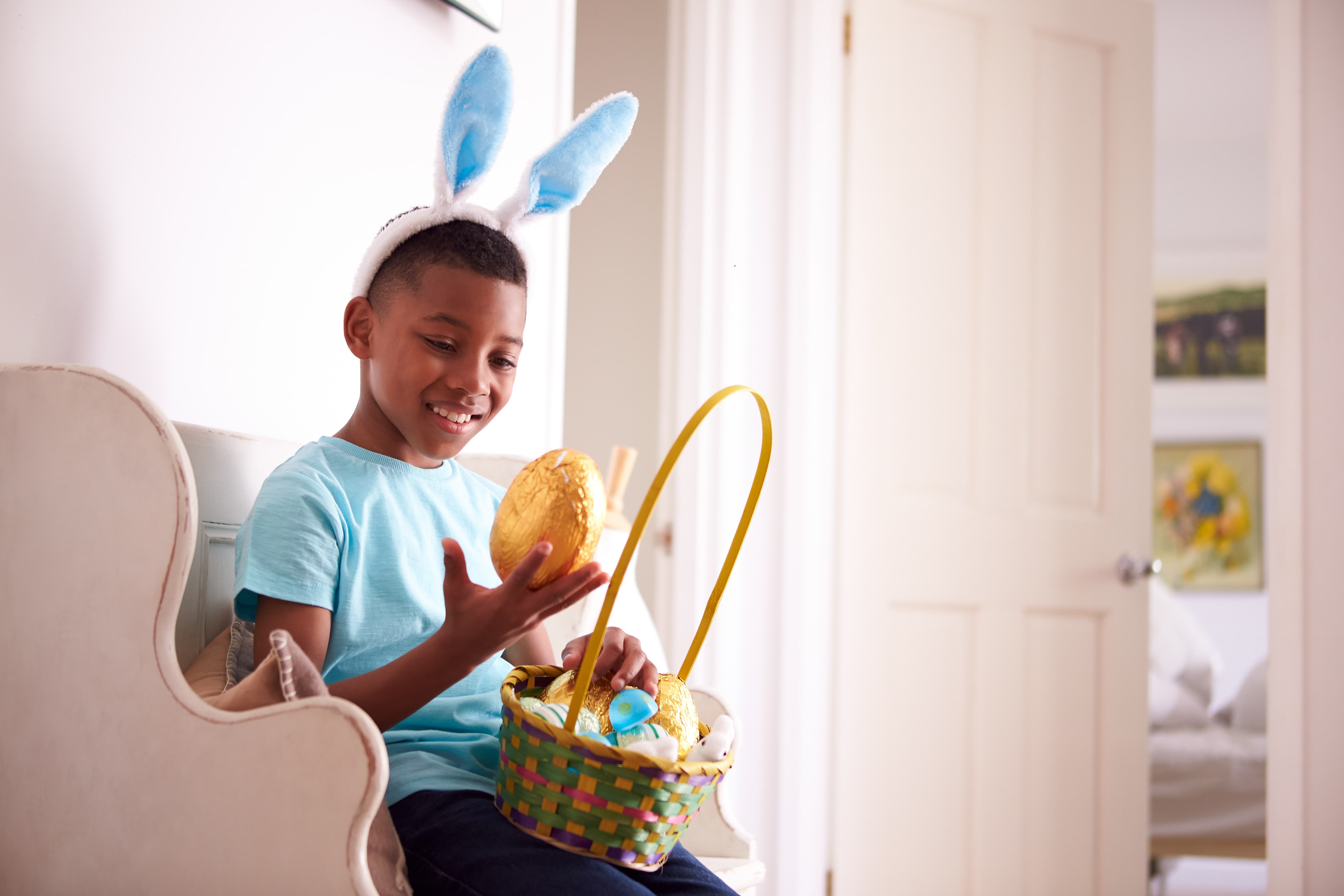menino negro usando adereço de orelhas de coelho e segurando ovo de Páscoa